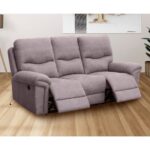 Sofá de tres plazas reclinables modelo América tapizado en tela Nolia en color gris cemento, con mecanismo de palanca en los asientos laterales, ideal para una sala de estar moderna. El tapizado en tela antimanchas ofrece durabilidad y fácil mantenimiento. Ubicado en un ambiente acogedor con suelo de madera y decoración minimalista.