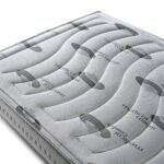 Parte superior de un colchón con una textura acolchada, diseñado con patrones ondulados y tejidos elásticos en color gris. En la superficie se puede leer la palabra "medical comfort", lo que sugiere que el colchón está diseñado para ofrecer comodidad médica o ergonómica. El material parece ser viscoelástico, proporcionando soporte adaptable al cuerpo.